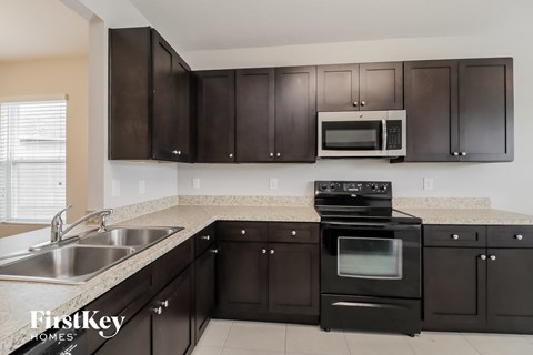 a kitchen with black cabinets and stainless steel appliances and a sink