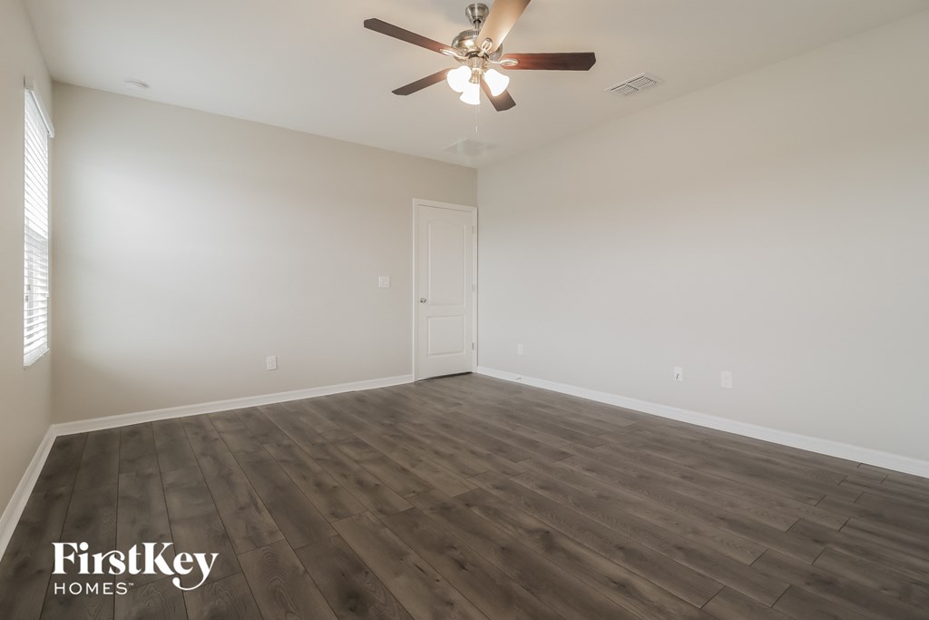 the spacious living room with wood flooring and a ceiling fan