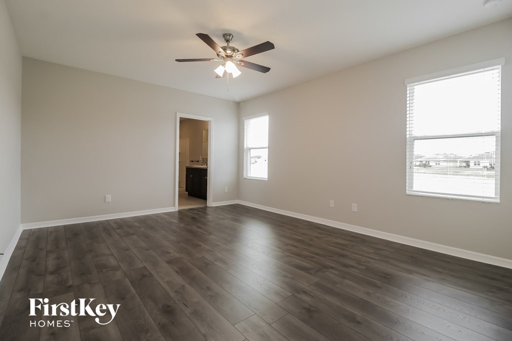 an empty living room with wood floors and a ceiling fan