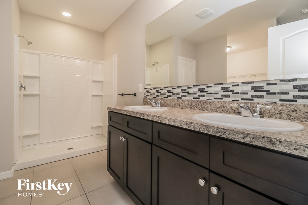 a bathroom with two sinks and a shower and a mirror