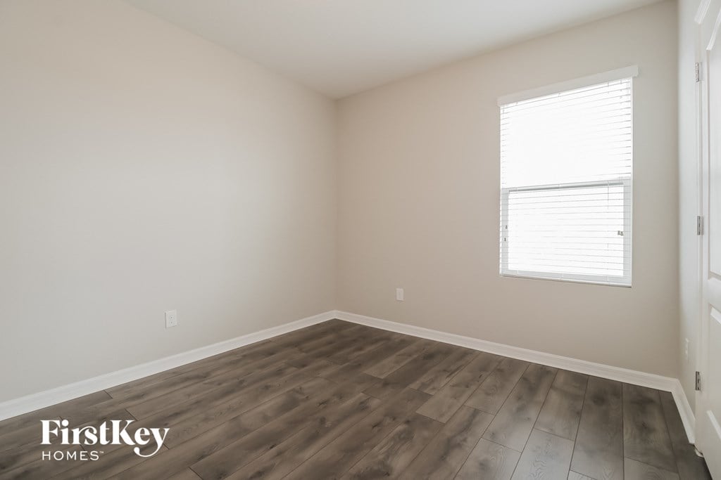 an empty room with wooden floors and a window