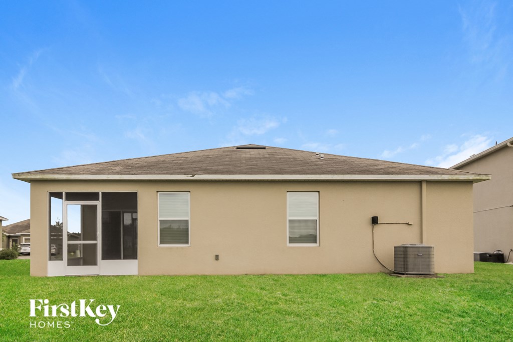 a small tan house with a grass yard and a blue sky