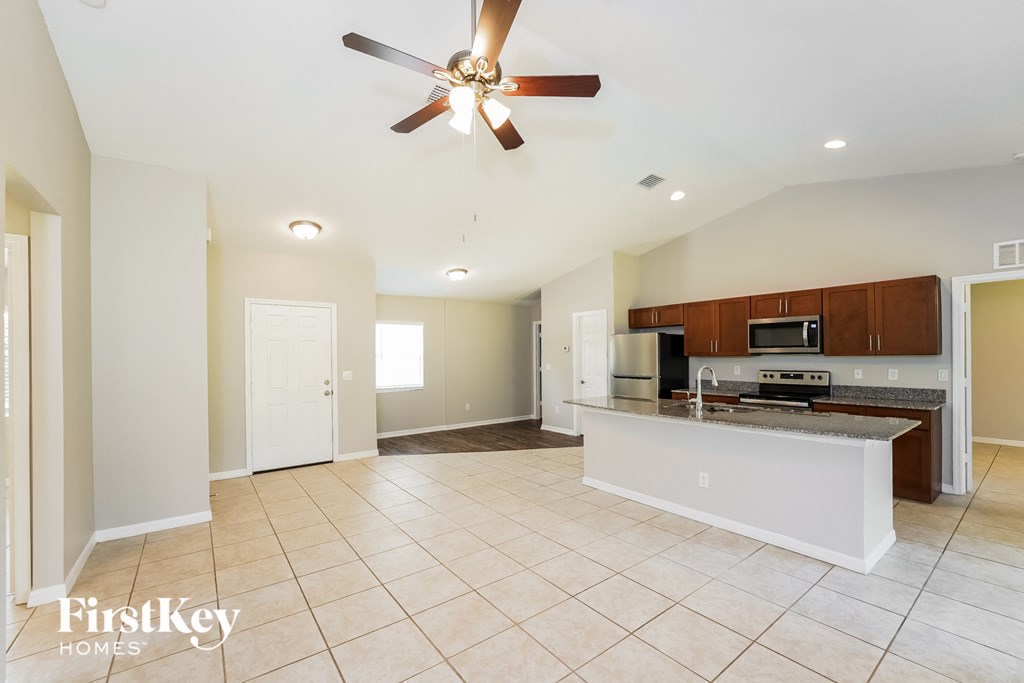 an open kitchen and living room with an island and a ceiling fan