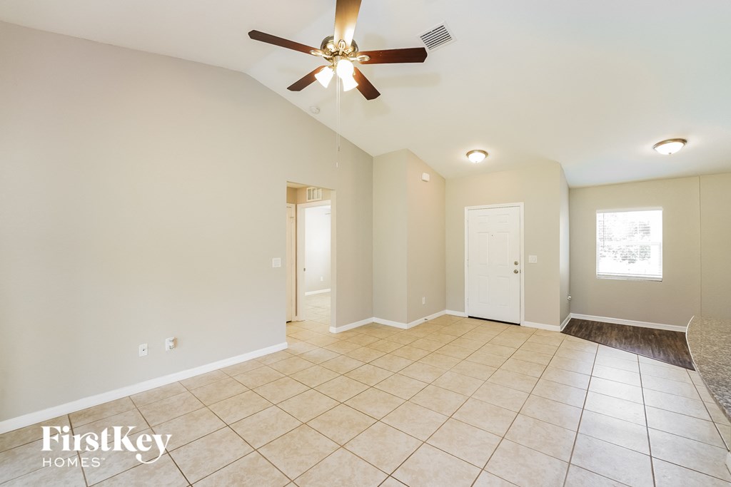 the spacious living room with ceiling fan and tile flooring