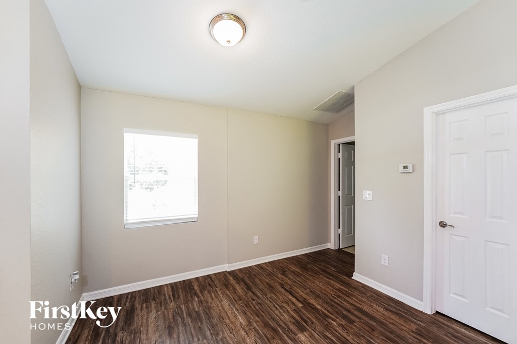 a bedroom with white walls and wood flooring and a white door