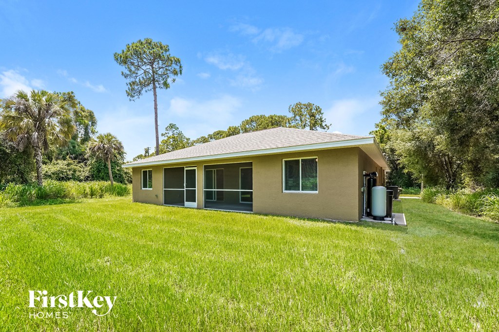 a small brown house with a grassy yard and trees
