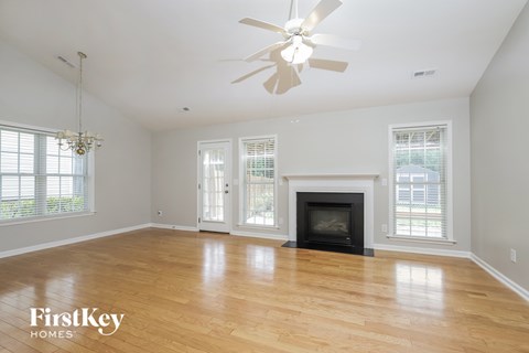 A spacious living room with a fireplace and a ceiling fan.