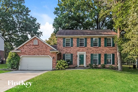 a brick house with green shutters and a white garage door