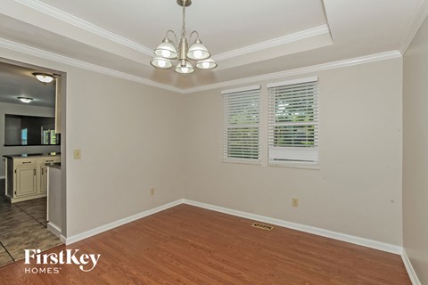 a dining room with wood floors and white walls and a chandelier