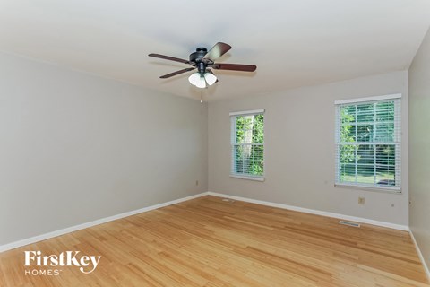 a bedroom with wood floors and a ceiling fan