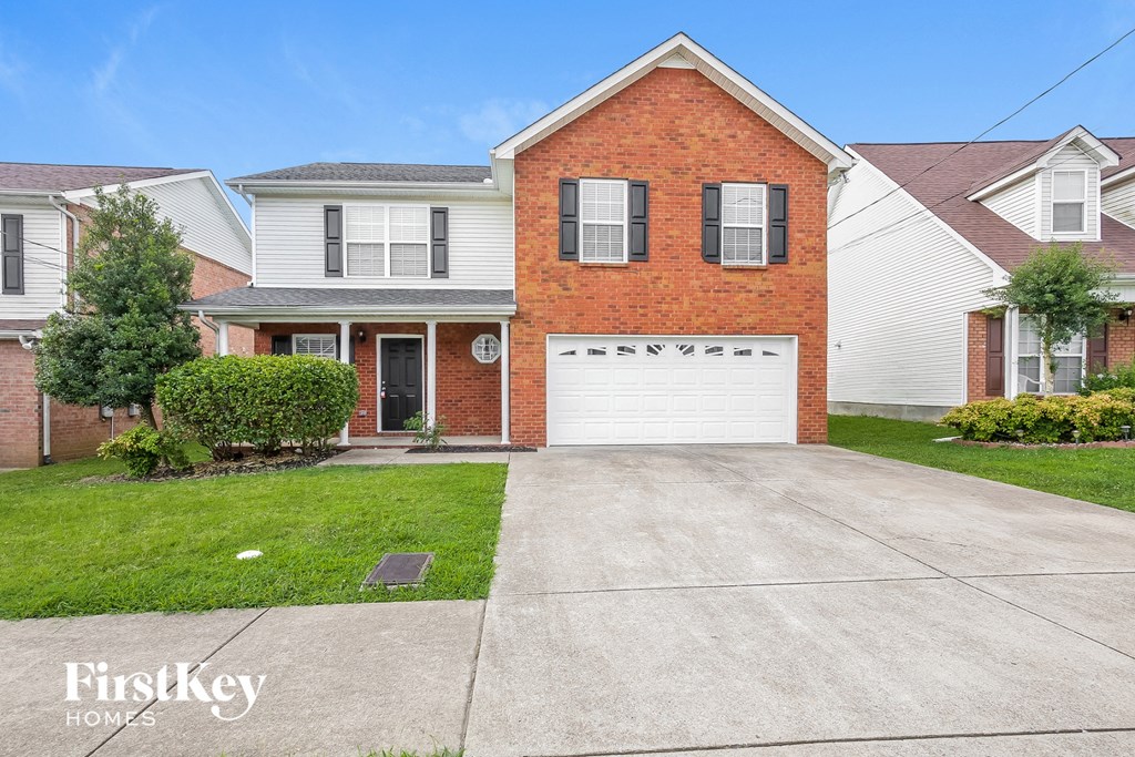 a clean driveway in front of a brick house with a white garage door