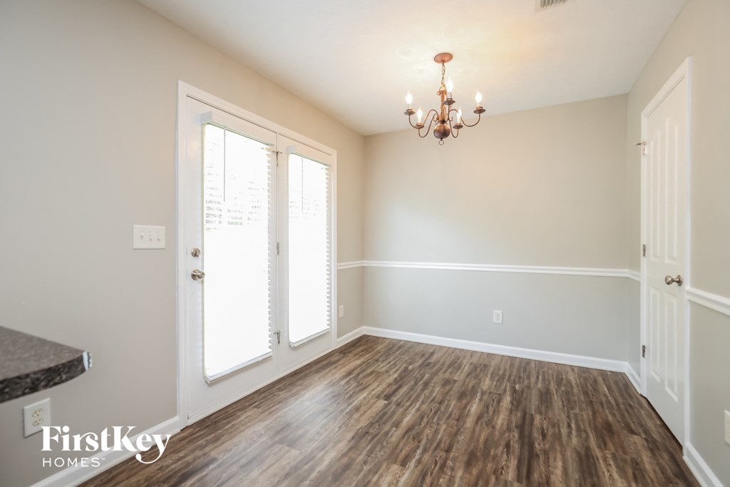 an empty living room with wood floors and a chandelier