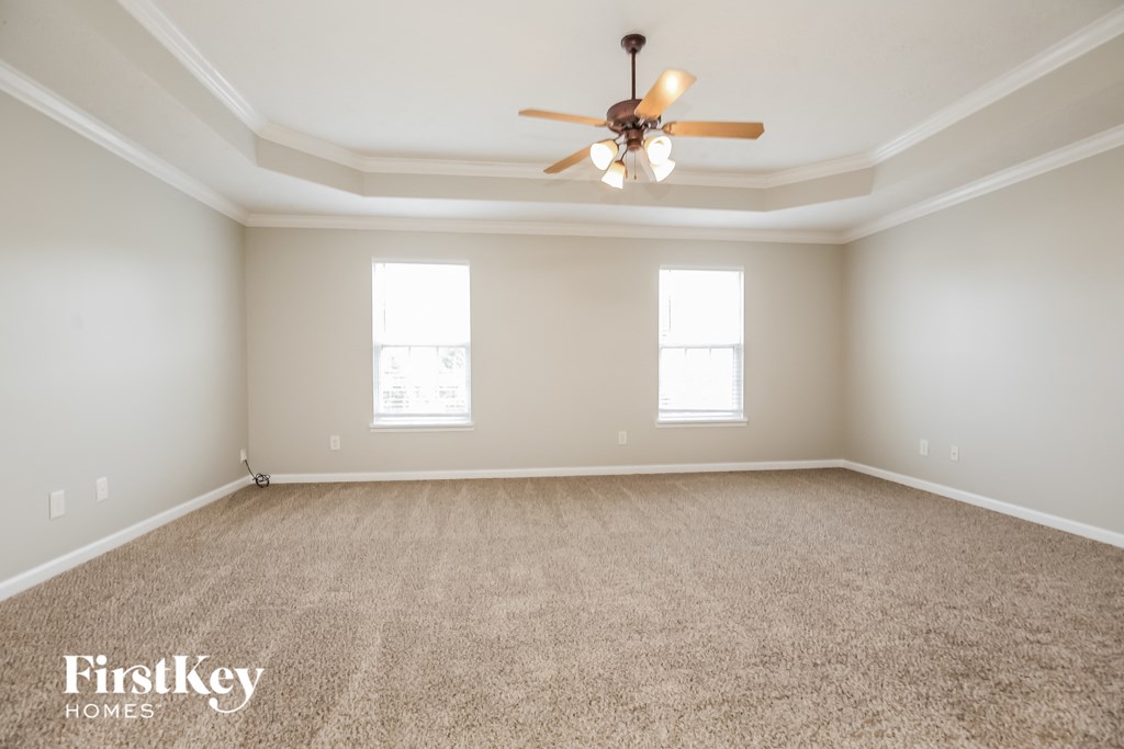 the spacious living room with ceiling fan and carpeting