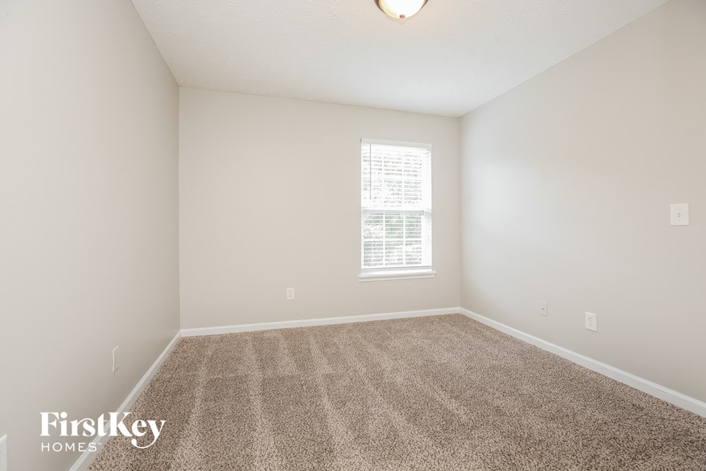 a spacious living room with carpet and a window