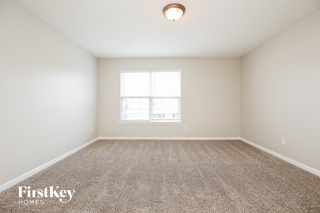 a spacious living room with carpet and a window