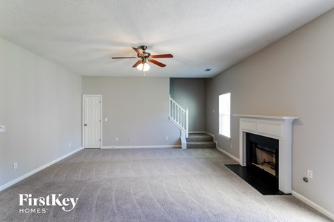 the spacious living room with fireplace and ceiling fan