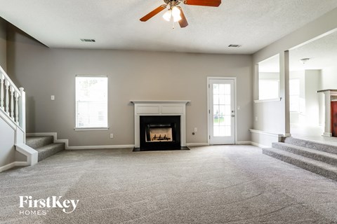 an empty living room with a fireplace and stairs