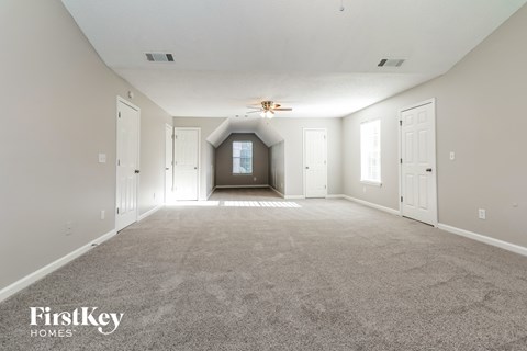 an empty living room with carpet and a ceiling fan