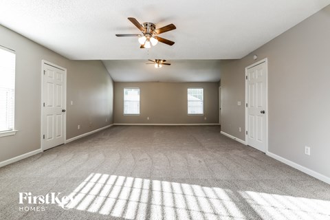 an empty living room with two doors and a ceiling fan