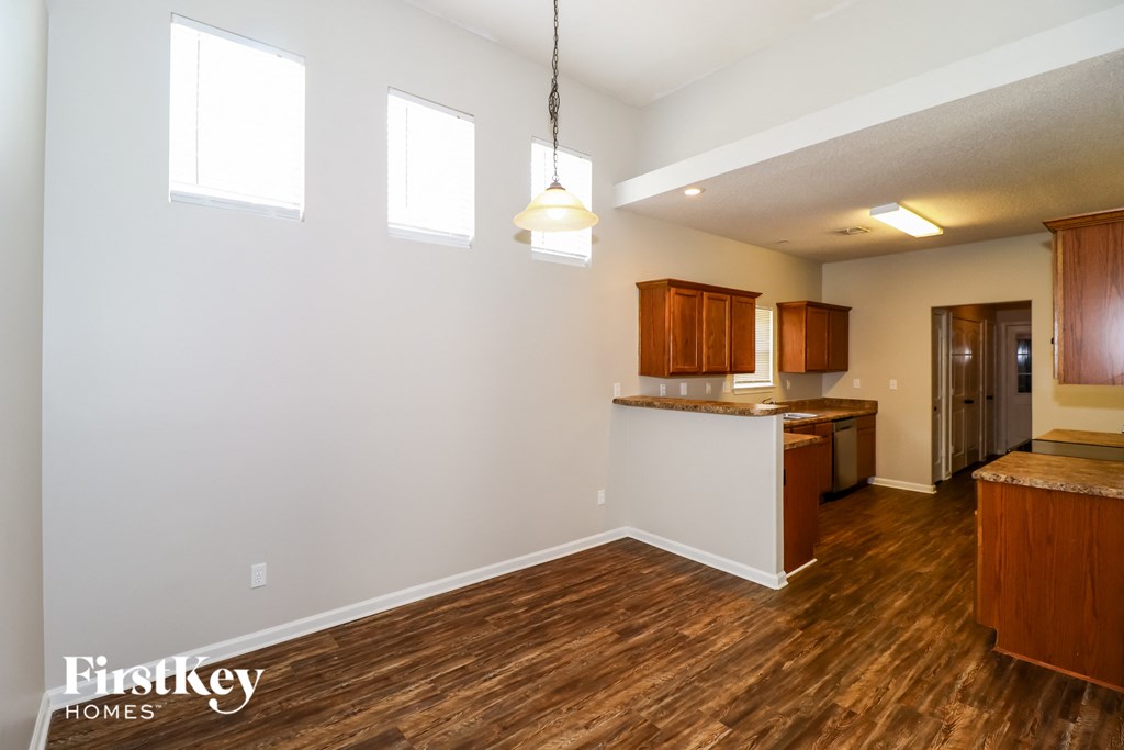 the kitchen and dining area of an empty kitchen and living room with wood flooring