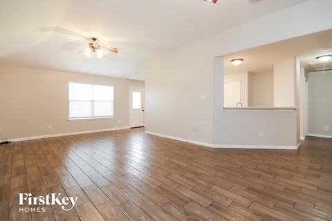 A spacious room with wooden flooring and a ceiling fan.