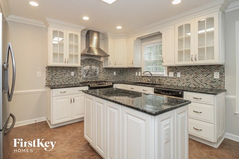 a white kitchen with granite counter tops and white cabinets