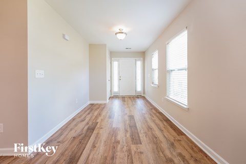 a living room with wood flooring and white walls and a white door