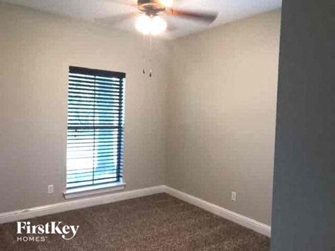 an empty bedroom with a ceiling fan and a window
