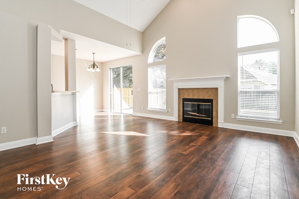 an empty living room with a fireplace and wooden floors