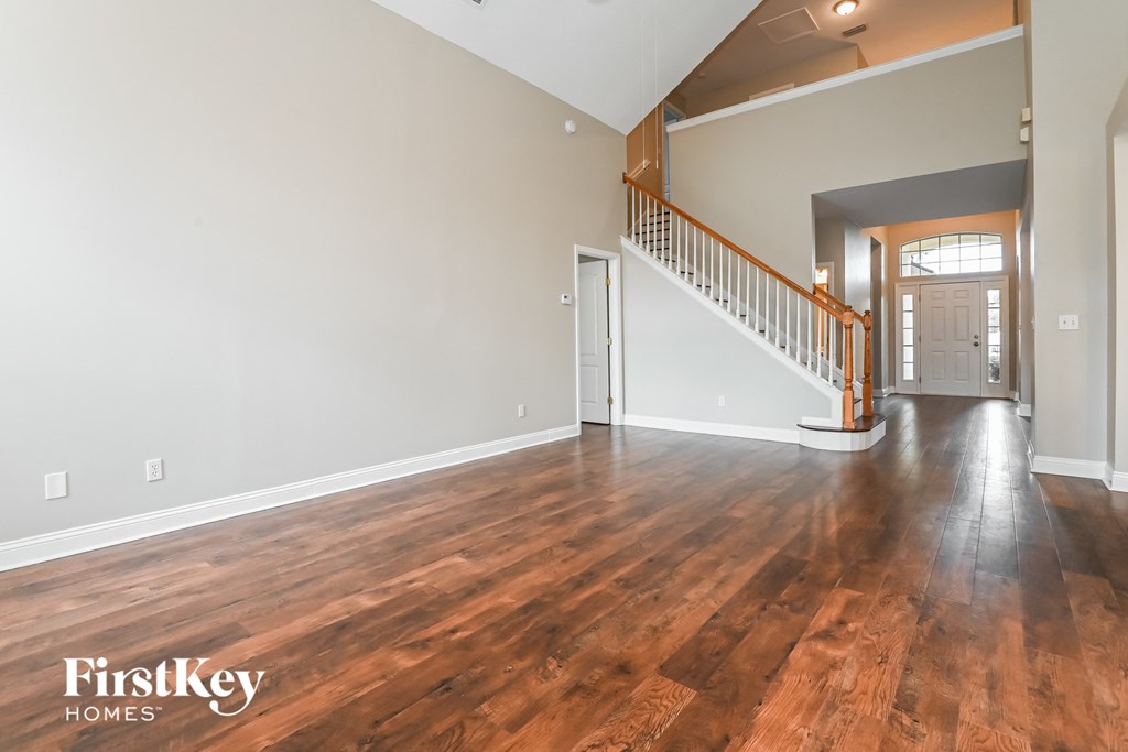 the living room and entryway of an empty house with wood flooring
