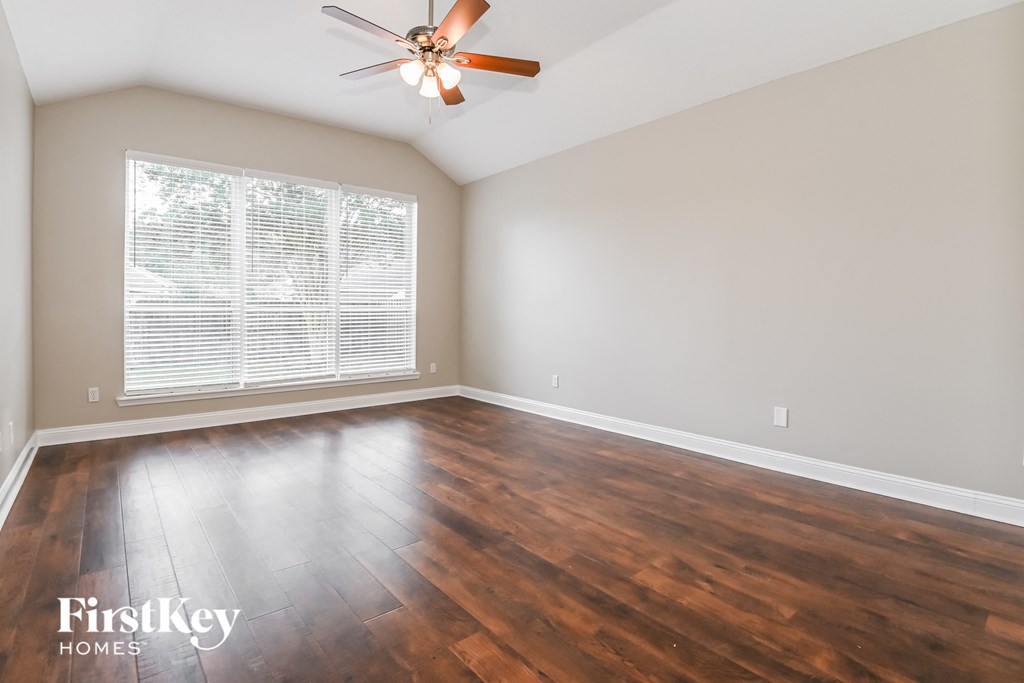 an empty living room with wood floors and a ceiling fan