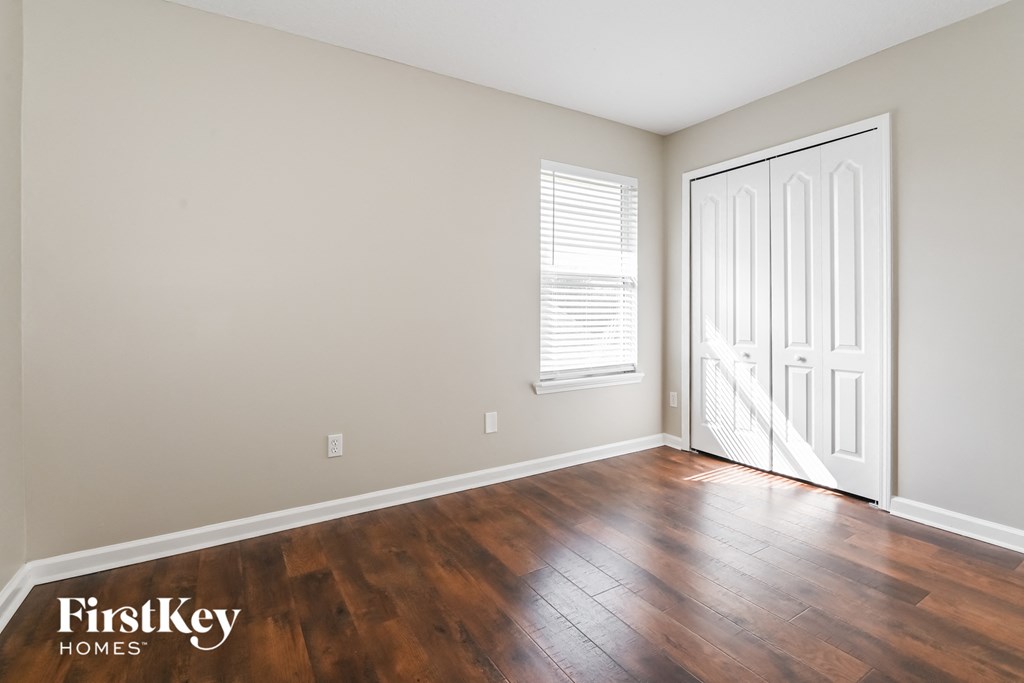 a living room with hardwood floors and a door to a bedroom