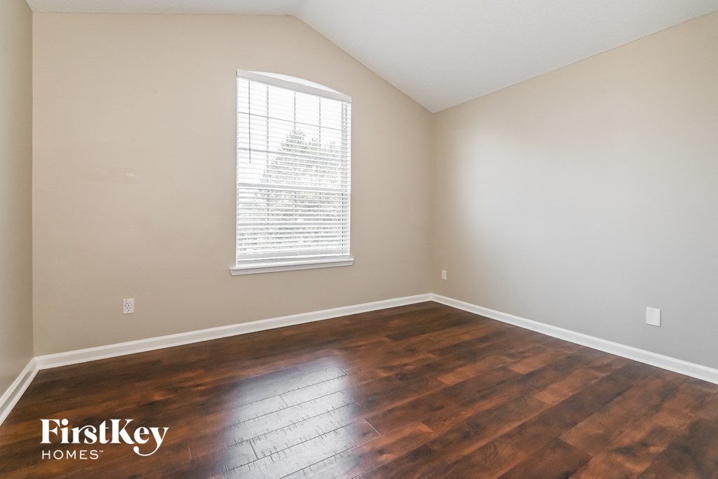 an empty room with wood floors and a window