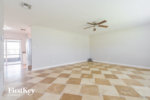 an empty living room with a ceiling fan and a checkered floor