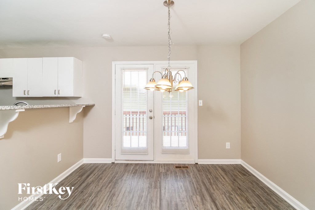 A well-lit room with a wooden floor and a white door.