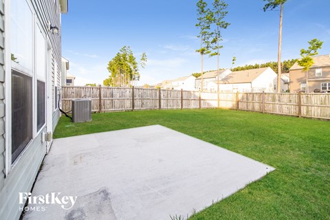 a backyard with a fence and green grass and a yard and a house
