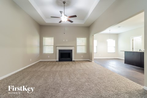 A spacious living room with a fireplace and a ceiling fan.
