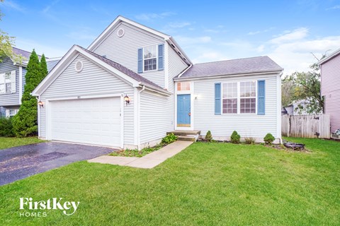 A two-story house with a garage and a well-maintained lawn.