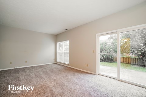 A room with a carpeted floor and a sliding glass door leading to a backyard.