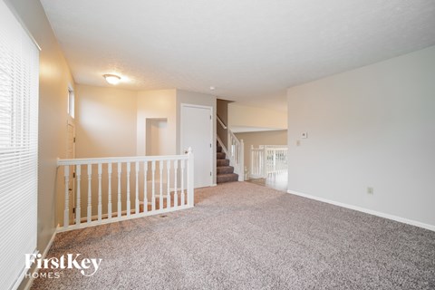 A spacious room with a staircase and a window with blinds.