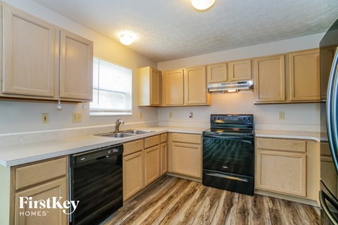 a kitchen with wooden floors and wooden cabinets and black appliances