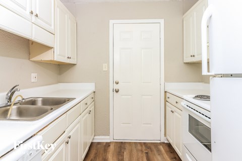 A white door is in the middle of a kitchen.