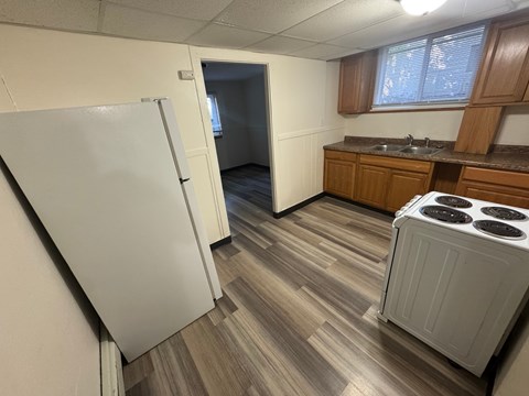 A kitchen with a white fridge, wooden cabinets, and a stove top oven.