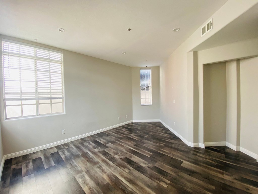 an empty living room with wood floors and a window