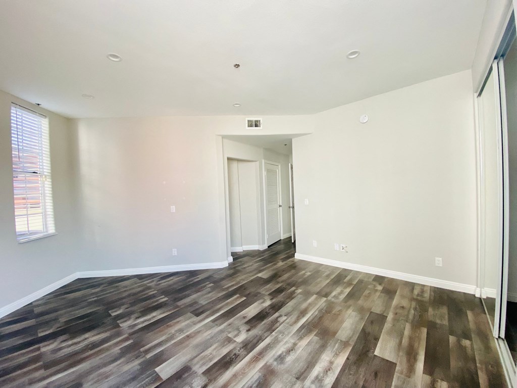 an empty living room with wood flooring and white walls