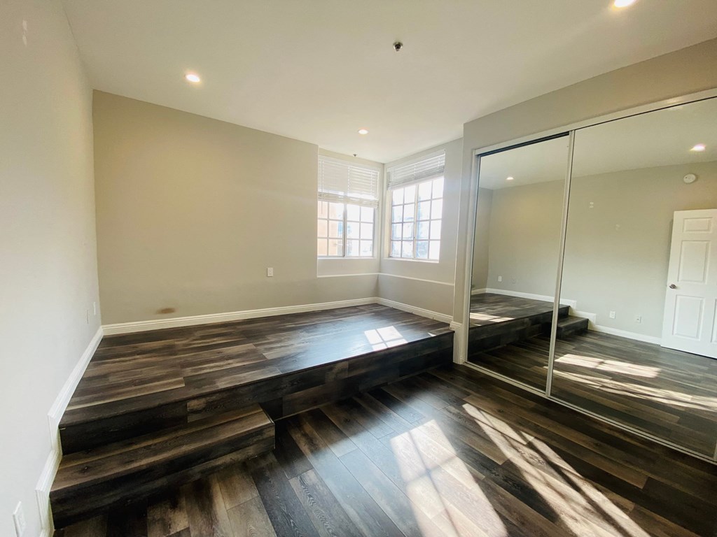 the master bedroom has a large window and hardwood floors