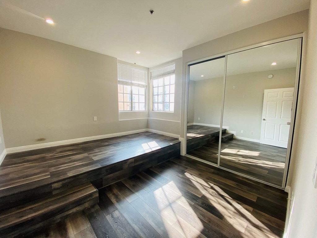 the master bedroom has a large window and hard wood flooring