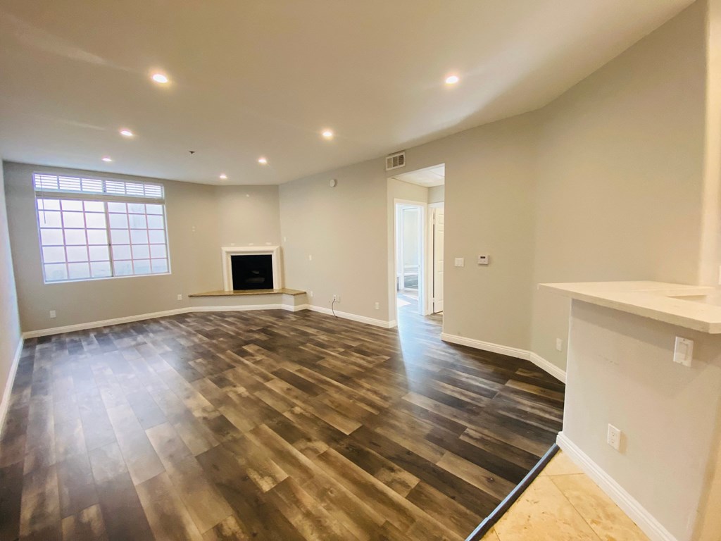 an empty living room with a fireplace and hardwood floors
