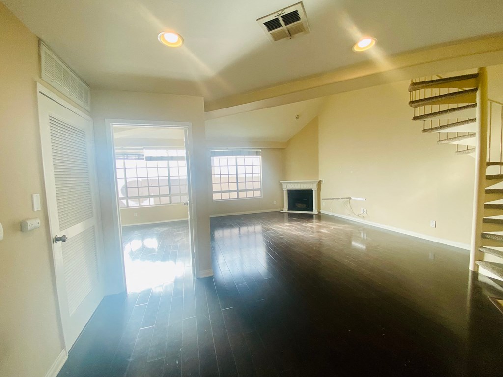 an empty living room with a staircase and a fireplace