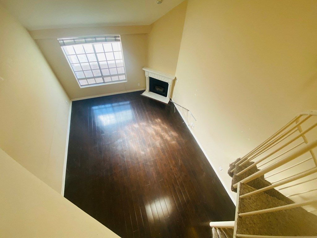 a living room with a wooden floor and a window and stairs